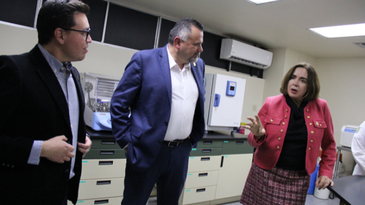 president adela de la torre speaking with 2 people in a lab