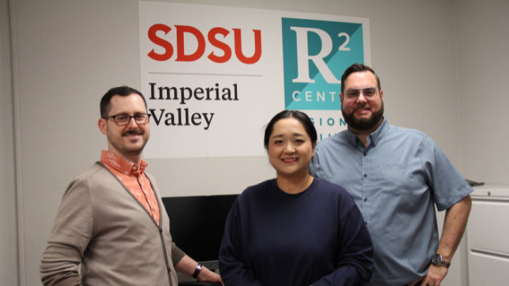 Professors at Imperial Valley posing behind an R1 poster