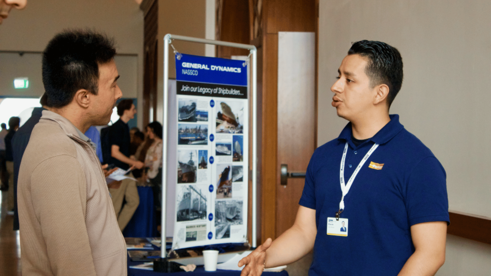 A man speaking with a recruiter at a career fair booth