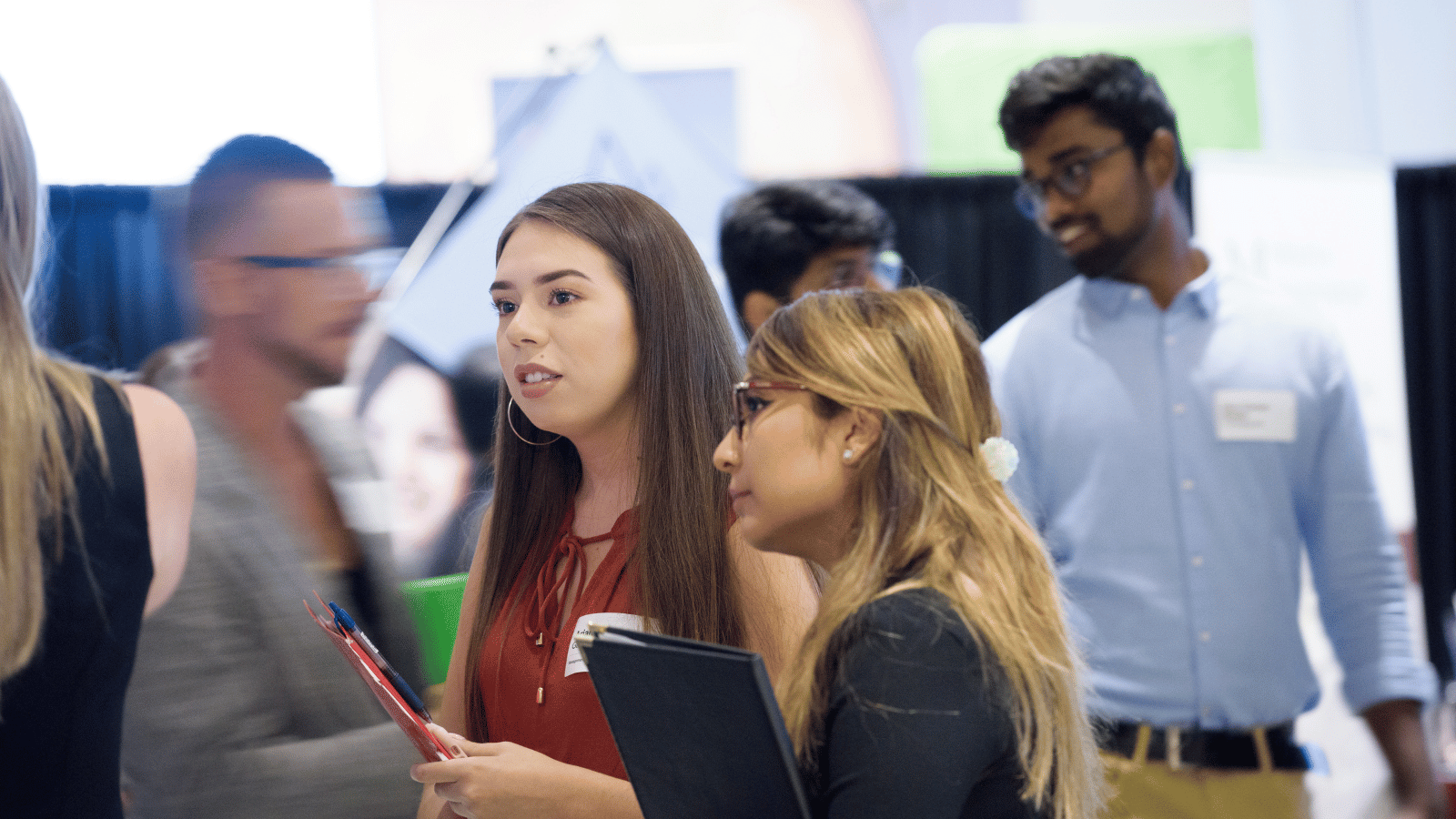 Two students speaking with two recruiters at a career fair table.