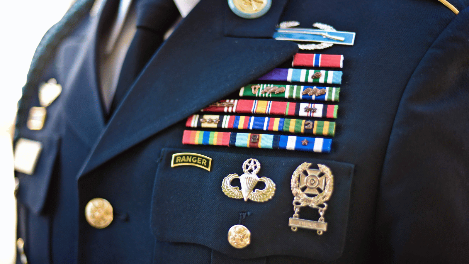 Closeup of a person's military uniform in which the chest area is decorated in ribbons and pins.